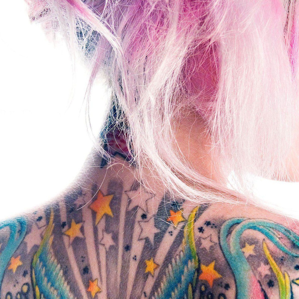 Девушка с розовыми волосами и татуировкой на спине