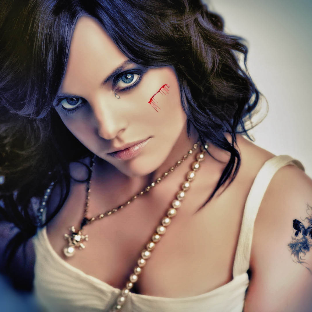 Шрам на щеке и татуировка на плече у девушки