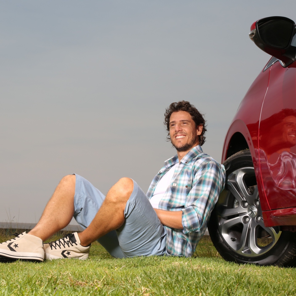 Мужчина сидит у колеса своего автомобиля