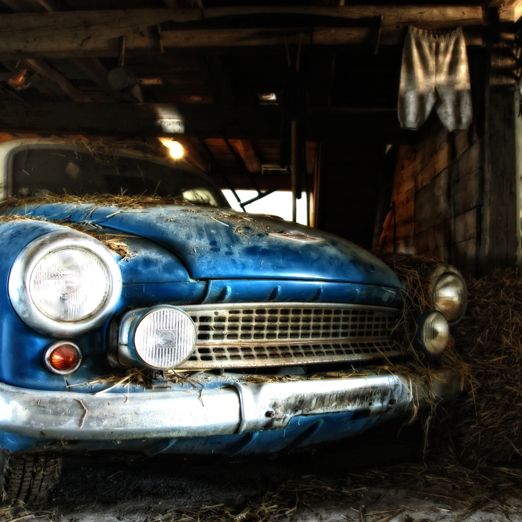 Старый автомобиль присыпан сеном в сарае