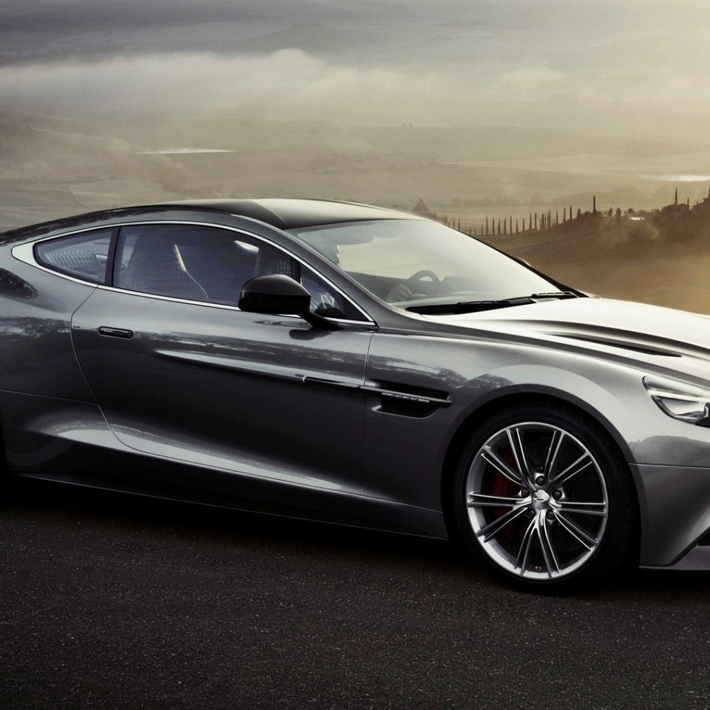 Темно серый Aston Martin на фоне туманной долины