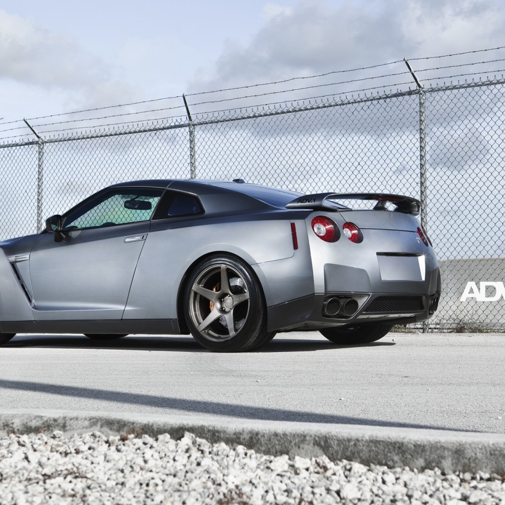 Серый Nissan Skyline GT-R R35 у забора из сетки