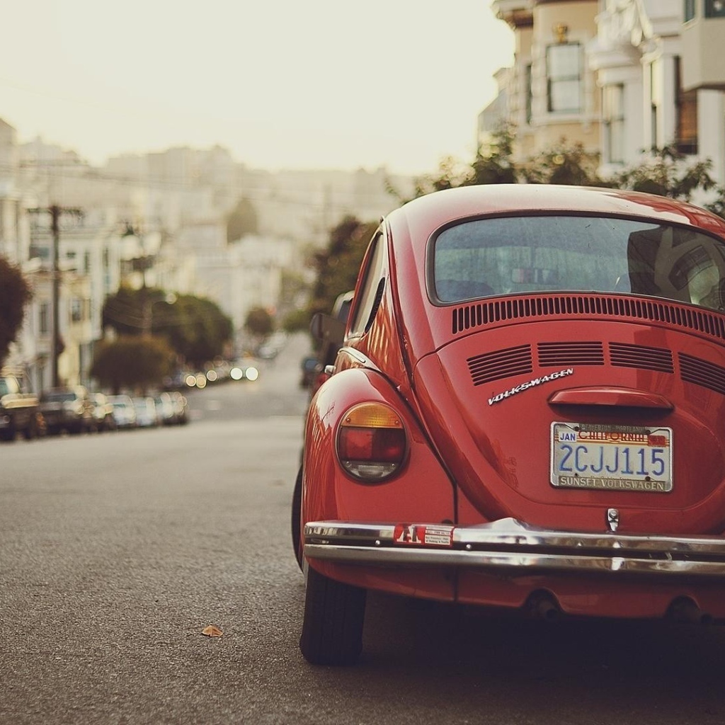 Красный Volkswagen Beetle припаркован на краю улицы