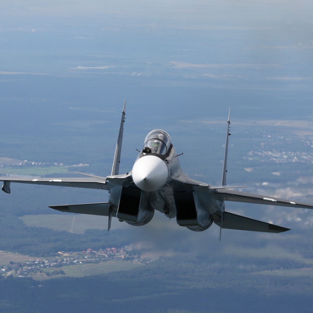 Самолет СУ-27 летит над городом