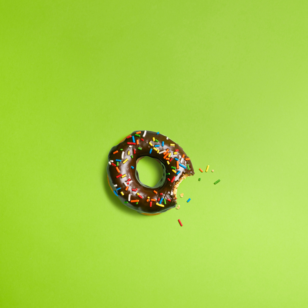 Шоколадный пончик на зеленом фоне