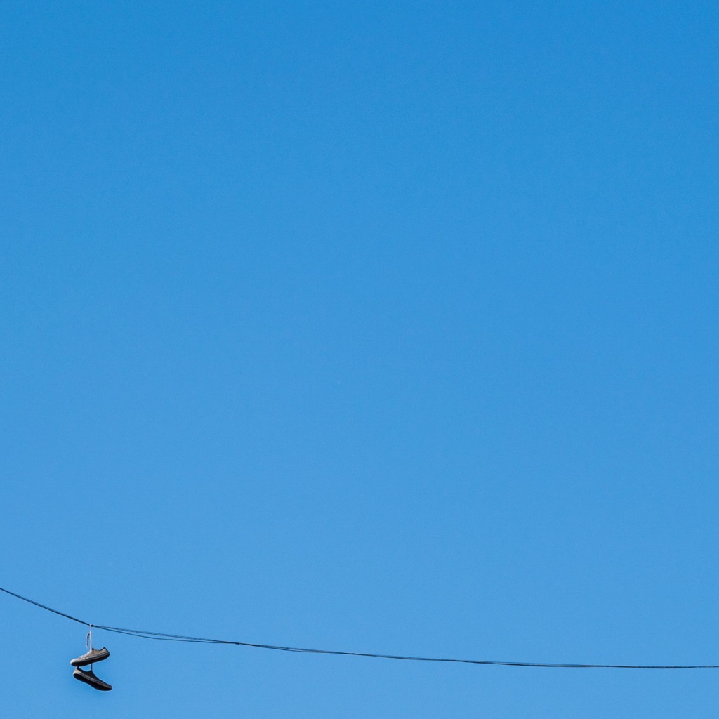 Кеды висят на проводе на фоне голубого неба