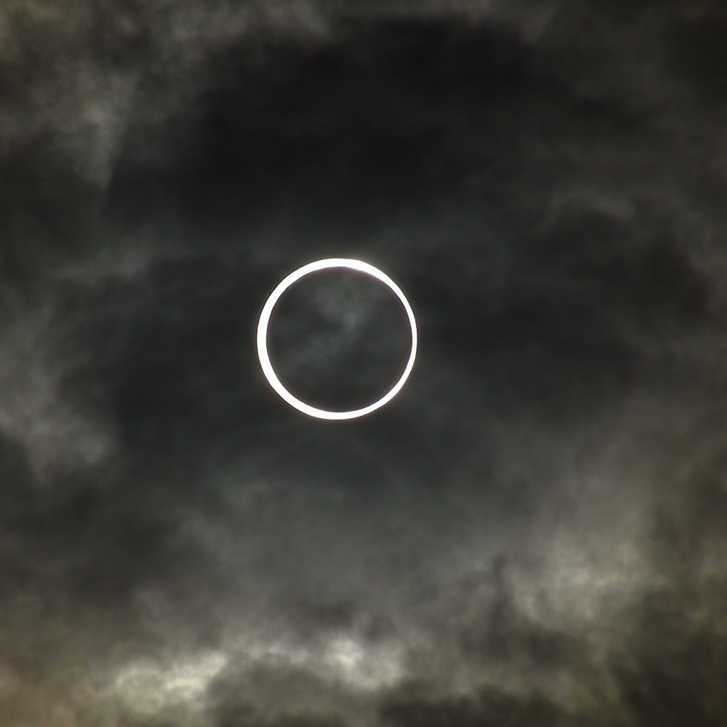 Белый круг на фоне темных облаков
