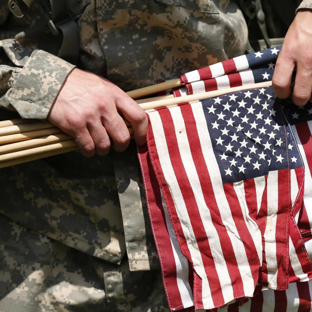 Солдат держит в руке флаги США