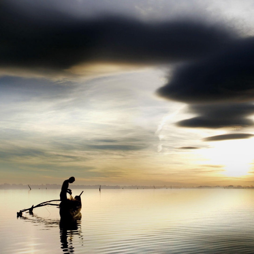 Рыбак достает улов из своей лодки