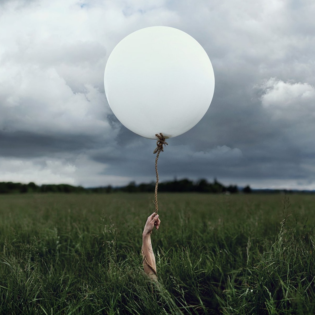 Рука с шаром среди поля