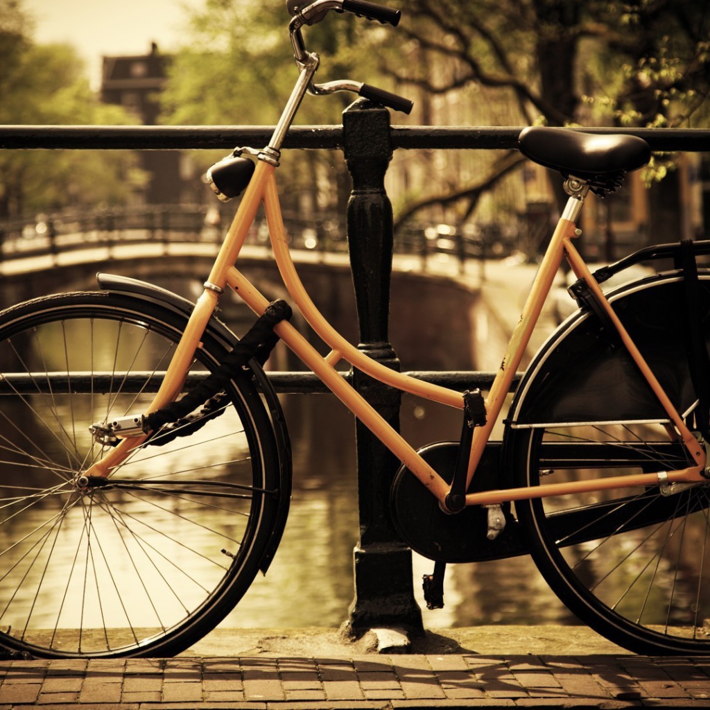 Оранжевый велосипед прислонен к перилам