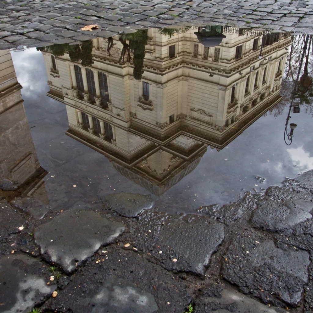 Отражение городского здания в луже