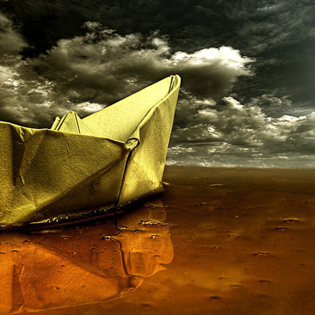 Корабль из бумаги на мокром песке