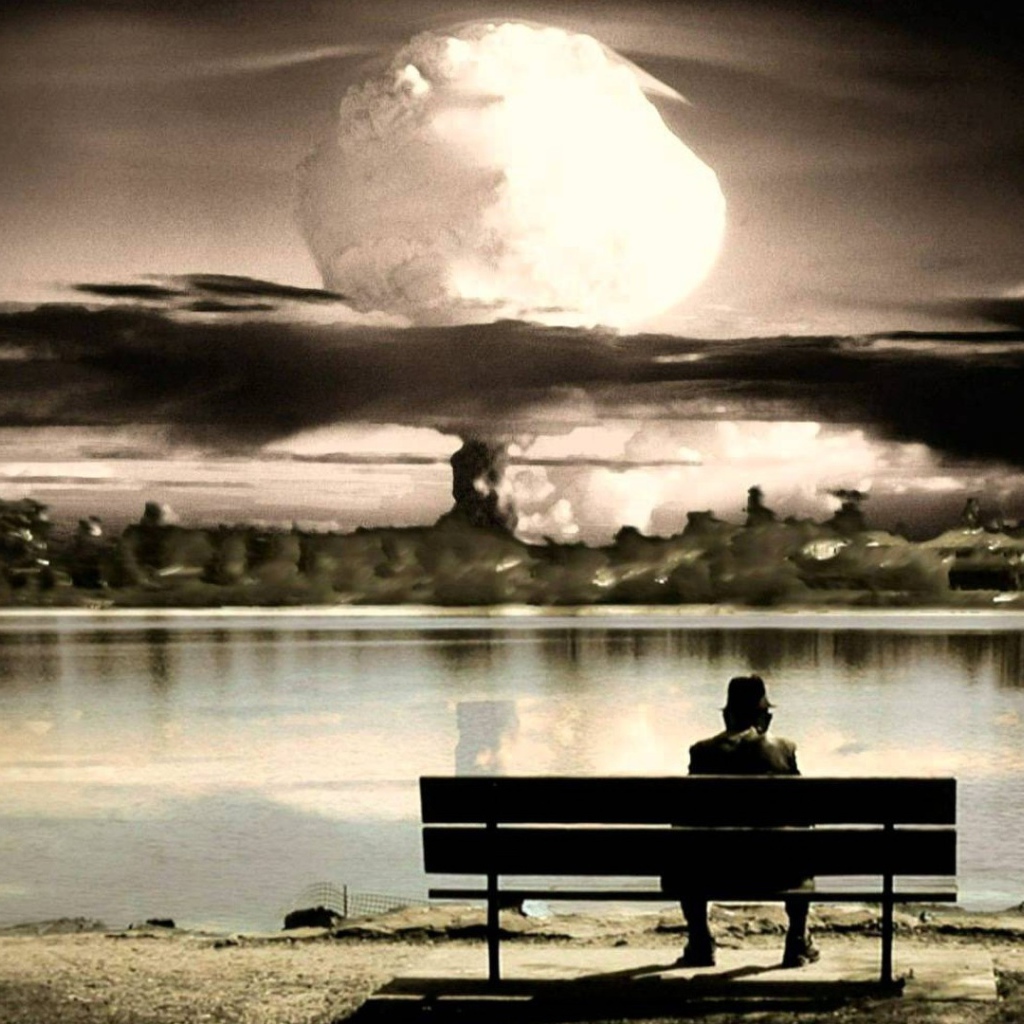 Человек смотрит на ядерный взрыв сидя на скамье