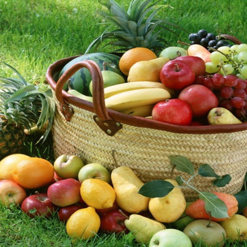 Корзина разнообразных фруктов на зеленом газоне