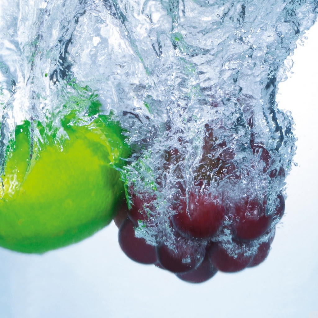 Зеленый лимон и кисть винограда в воде