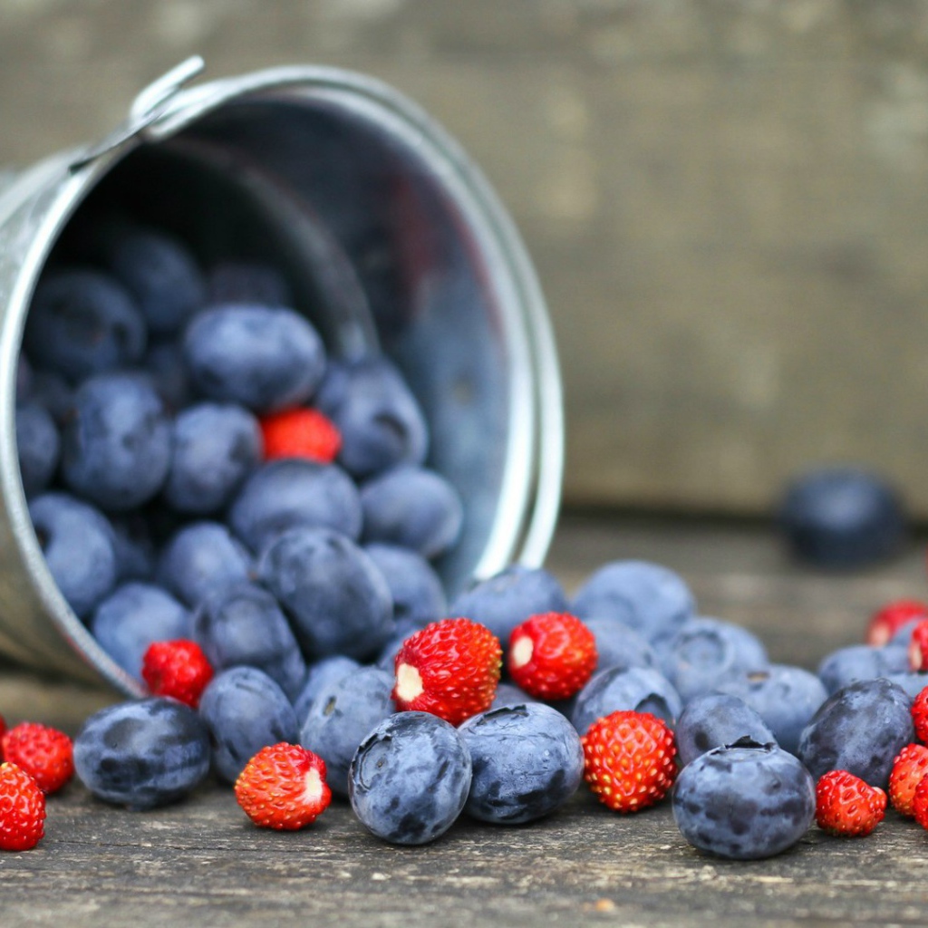 Плоды клубники и сливы в ведре