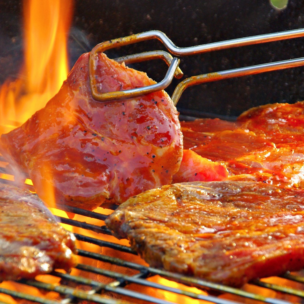 Стейк жарится на огне барбекю