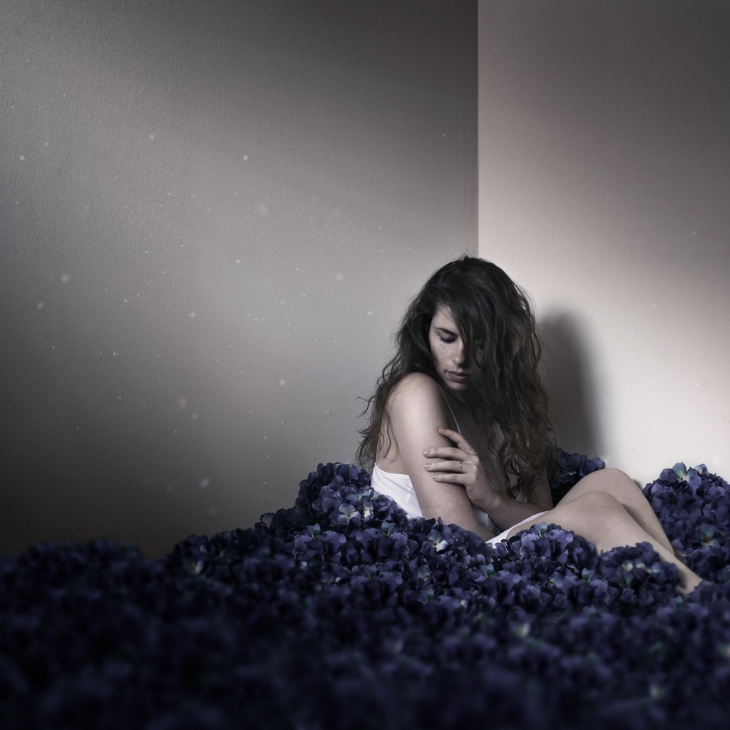 Девушка сидит в углу среди цветов