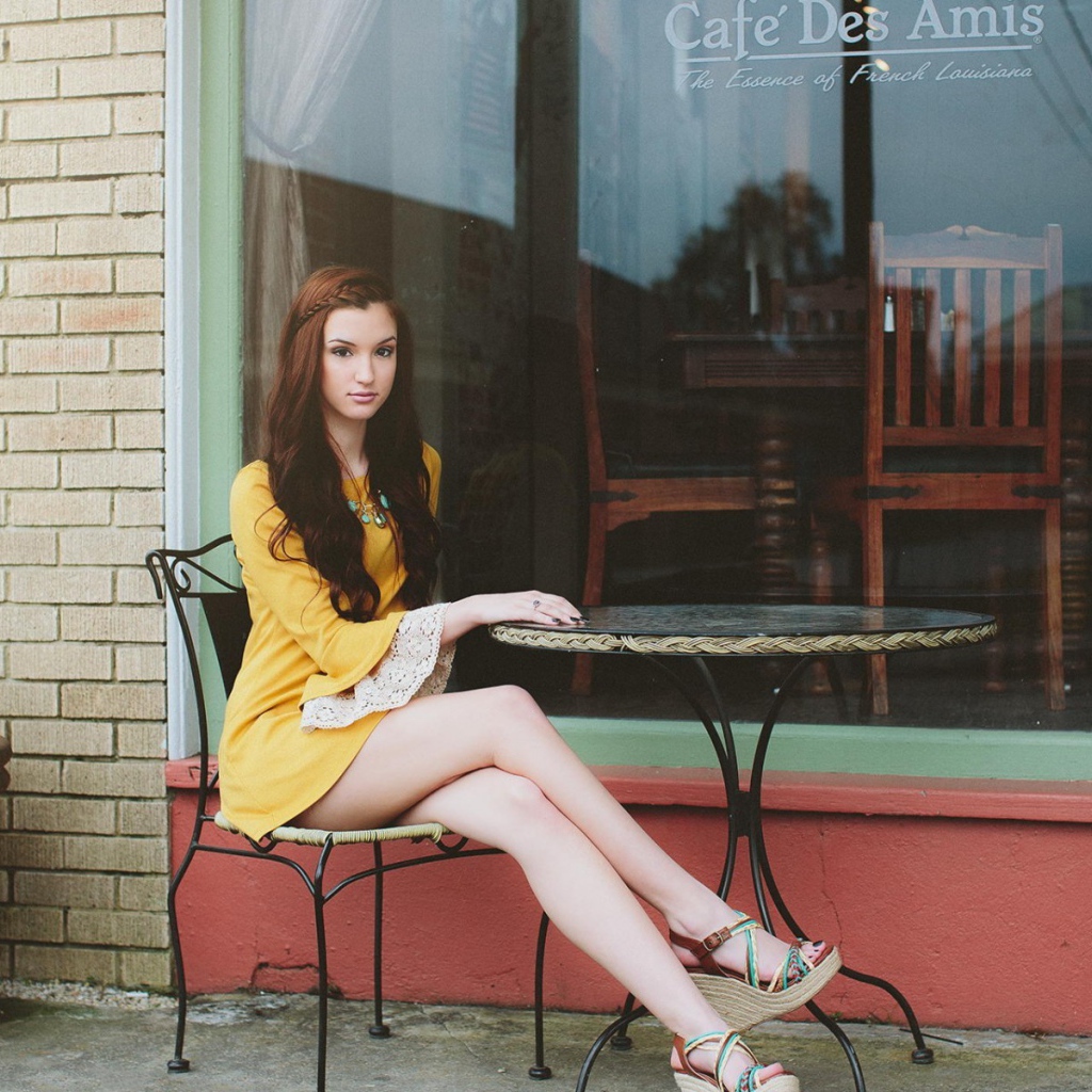 Девушка сидит за столиком уличного кафе