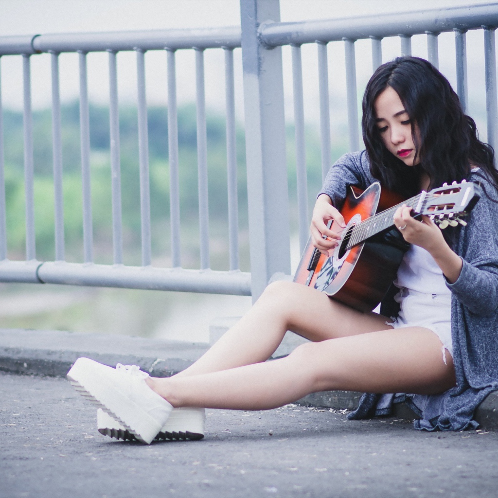 Азиатка брюнетка с гитарой на мосту