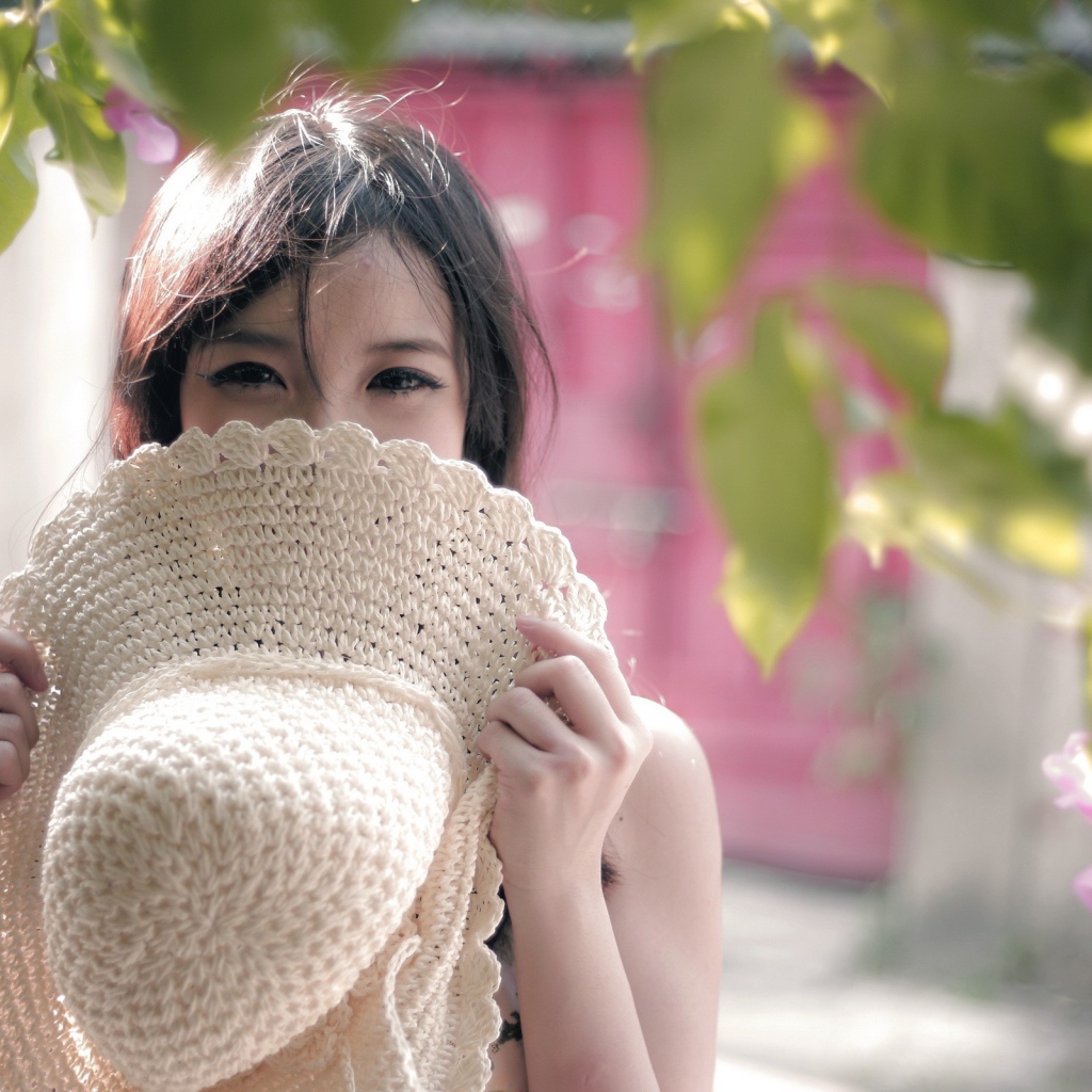 Азиатская девушка прикрыла лицо шляпой