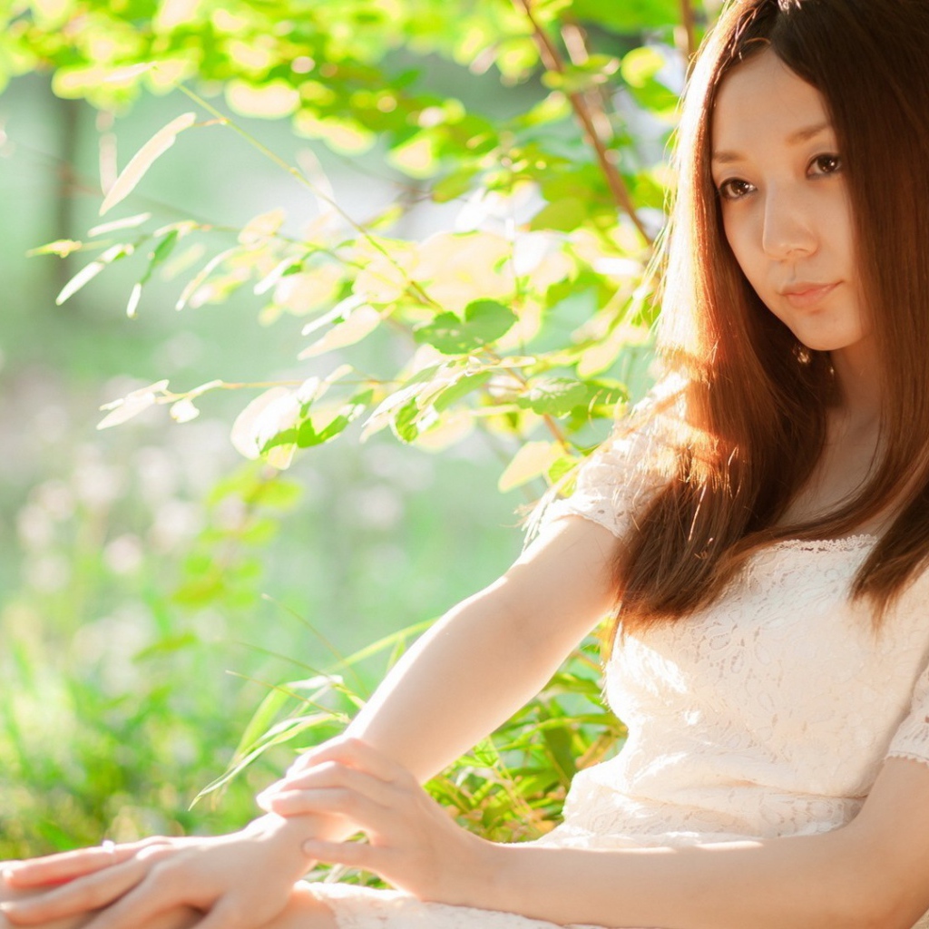 Азиатская девушка прислонилась спиной к дереву