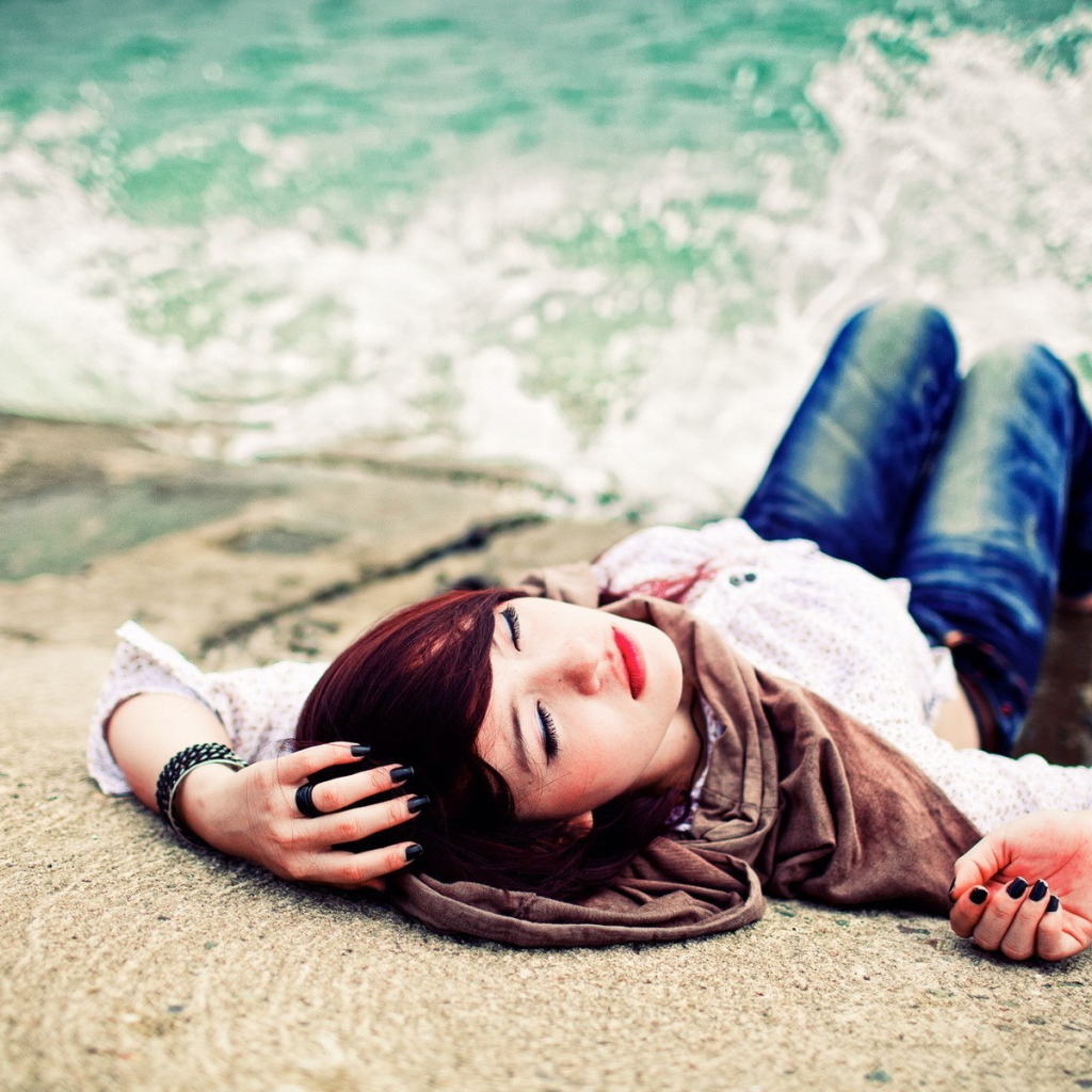 Босая девушка в джинсах лежит на набережной