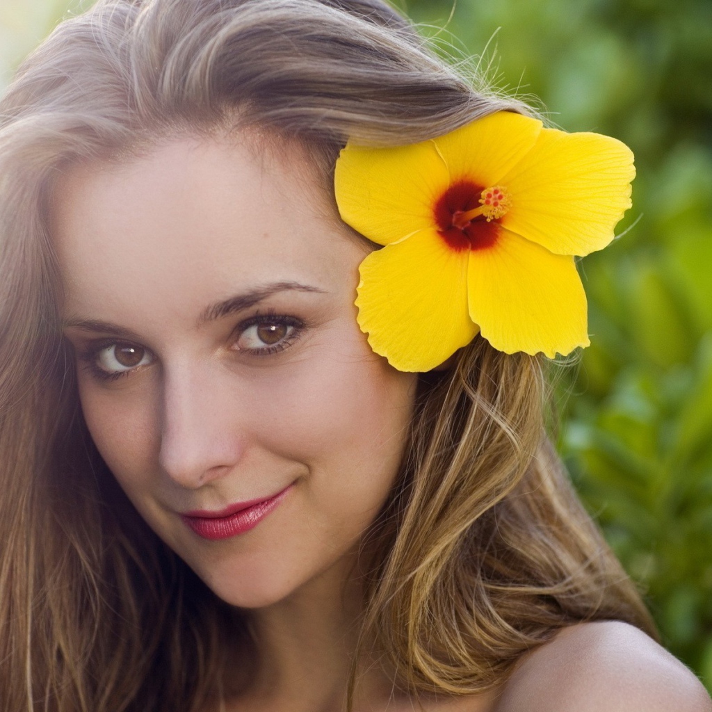 Большой желтый цветок в волосах у девушки