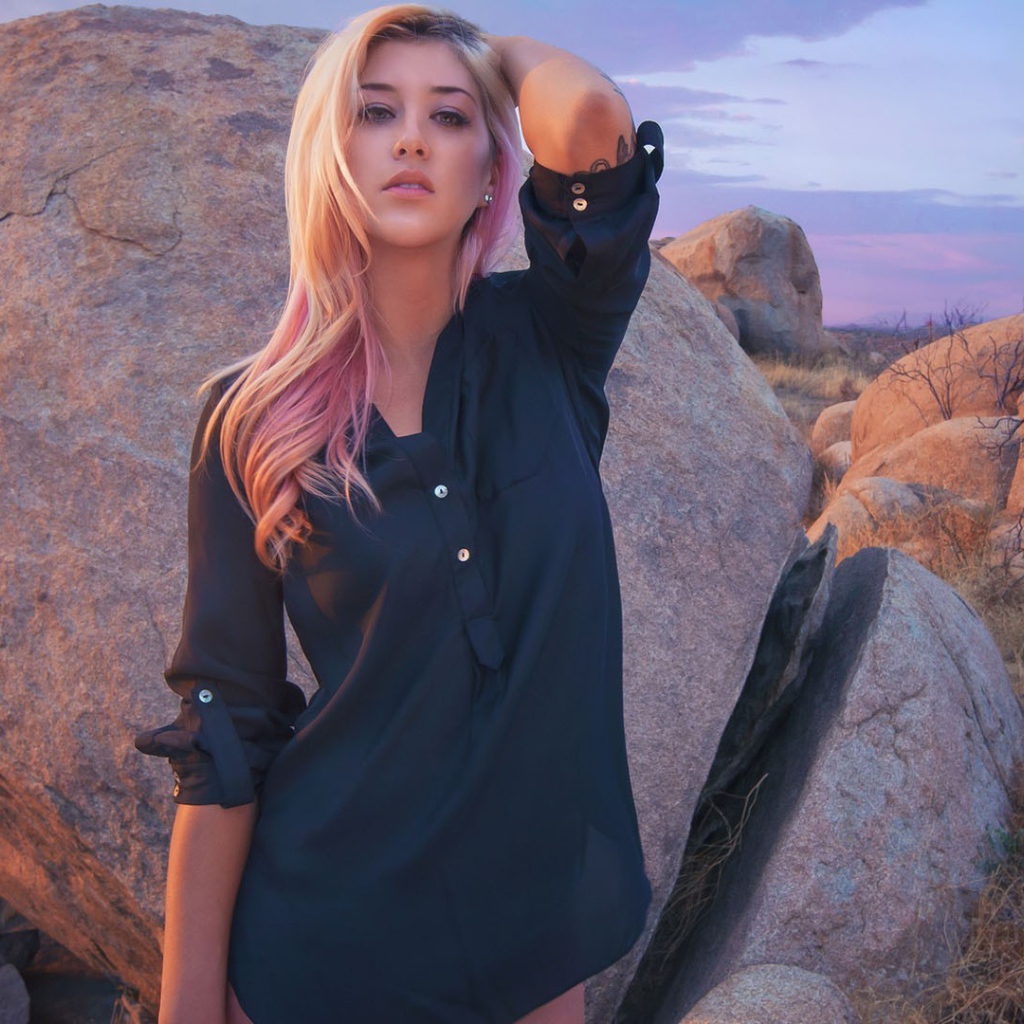 Блондинка стоит у большого валуна