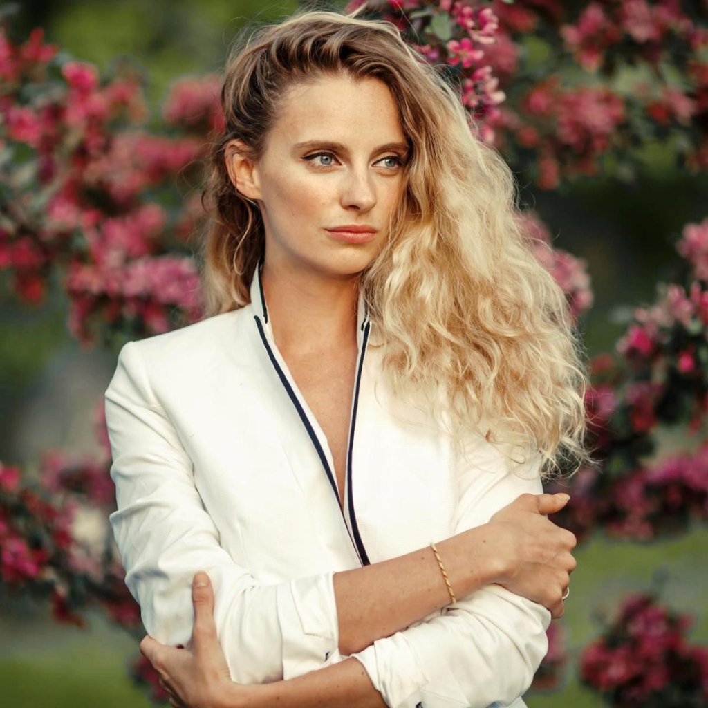 Голубоглазая блондинка на фоне цветущих деревьев