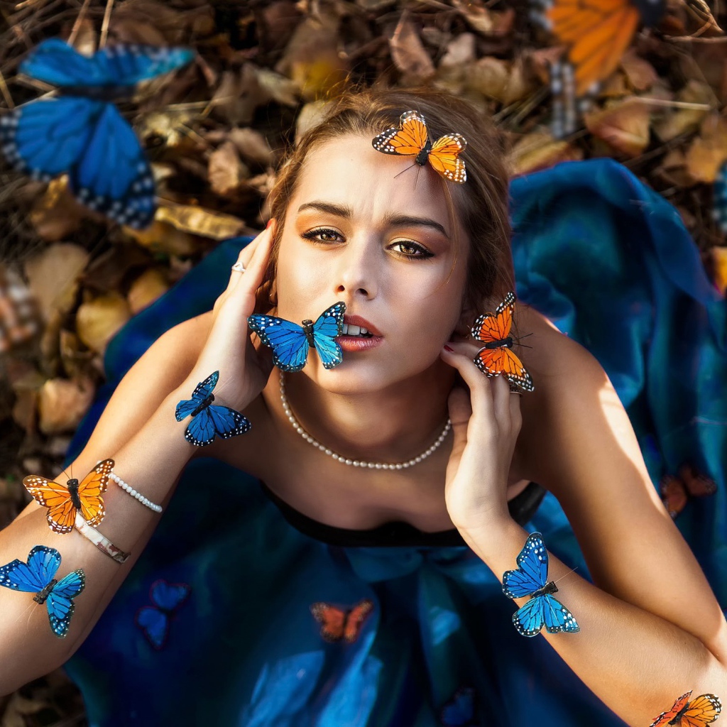 Голубые и оранжевые бабочки на девушке