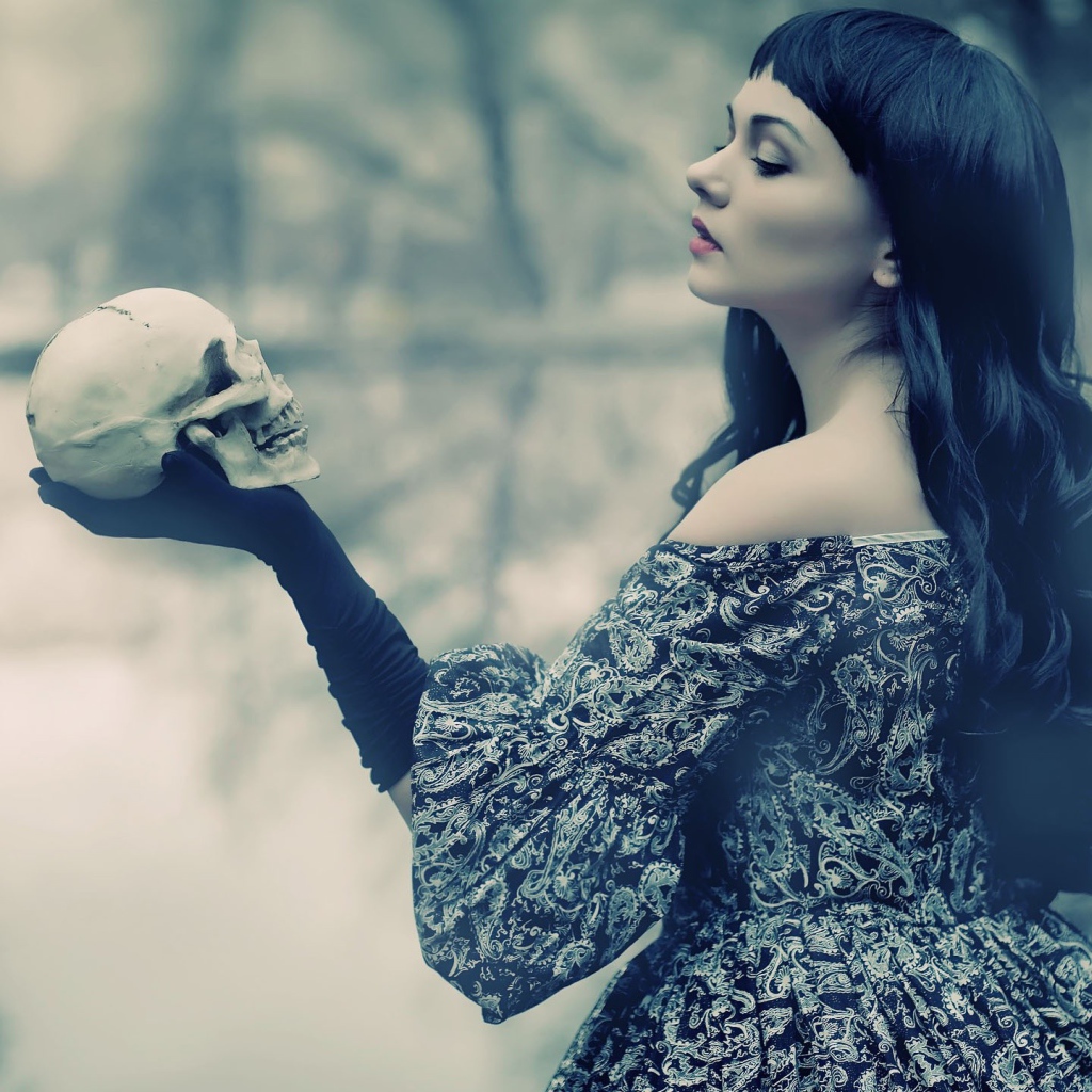 Брюнетка держит в руке череп