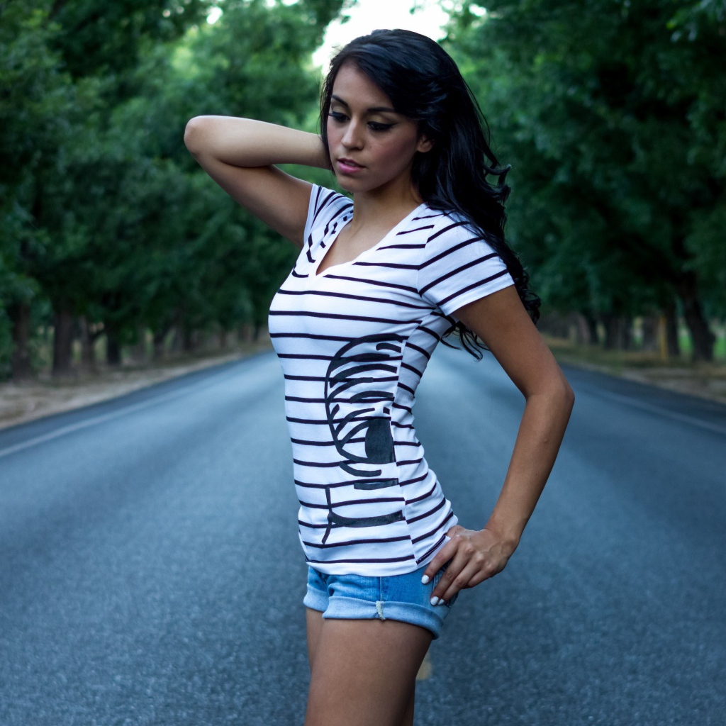 Брюнетка в джинсовых шортах среди дороги