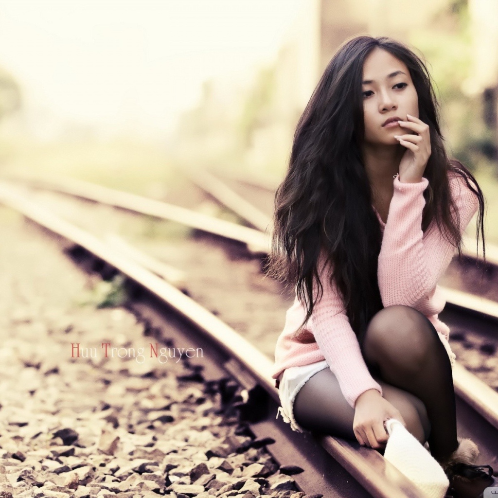 Брюнетка сидит на холодных рельсах