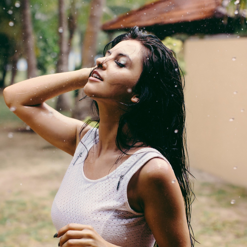 Брюнетка подставляет лицо под капли дождя