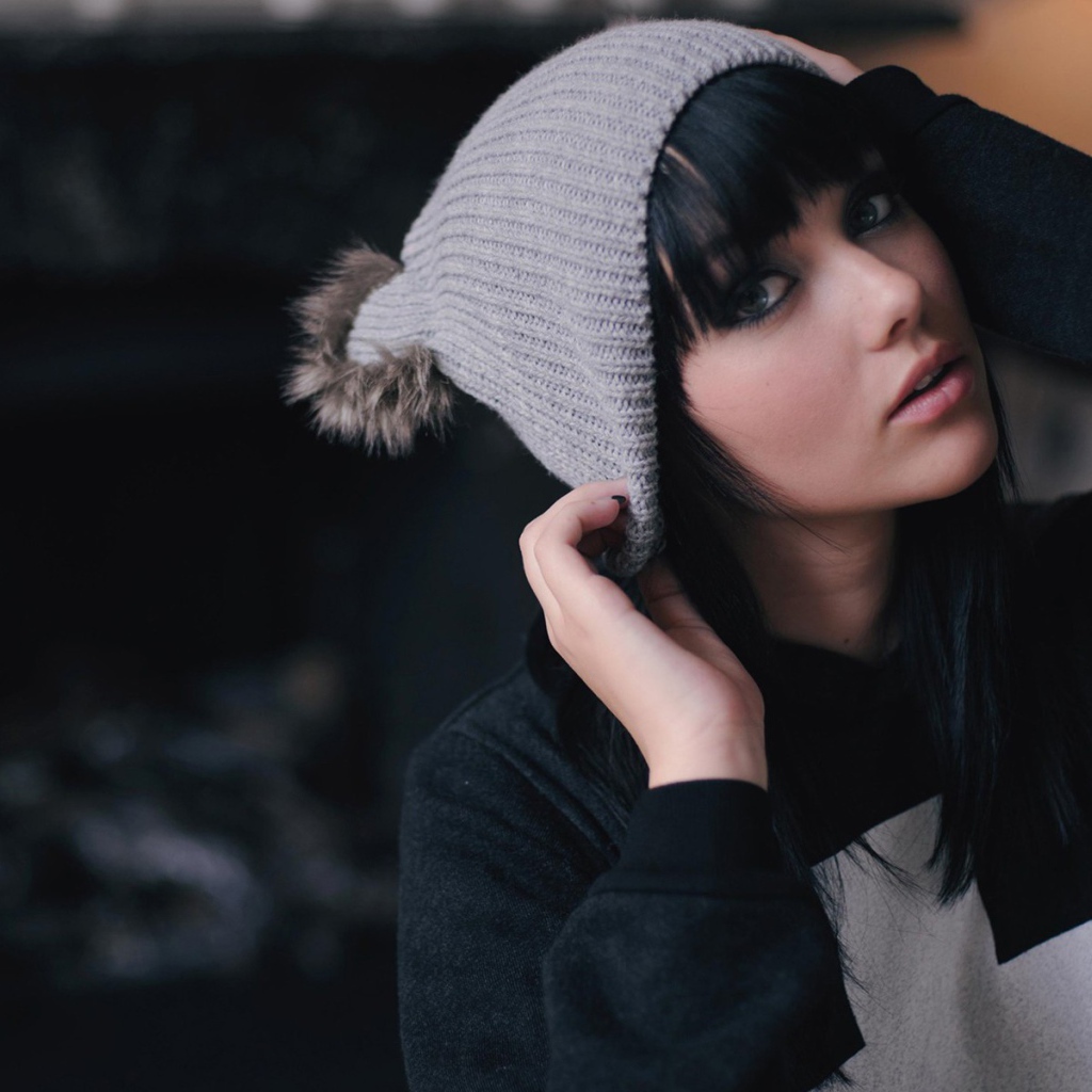 Брюнетка одевает вязаную шапочку