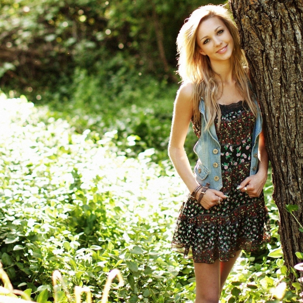 Милая блондинка прислонилась к дереву