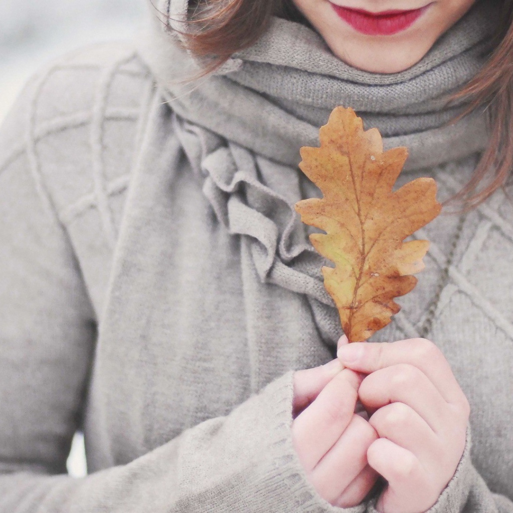 Девушка держит в руках желтый лист