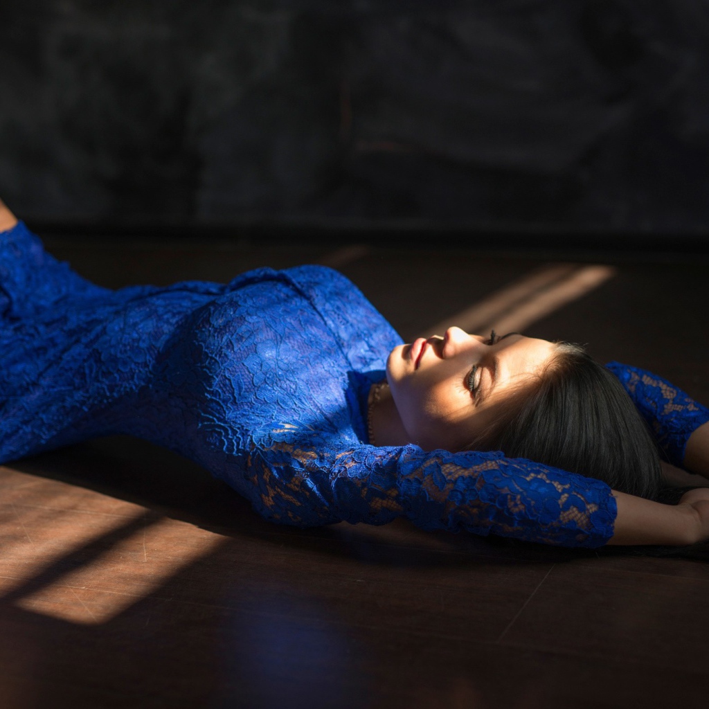 Девушка в голубом кружевном платье лежит на полу