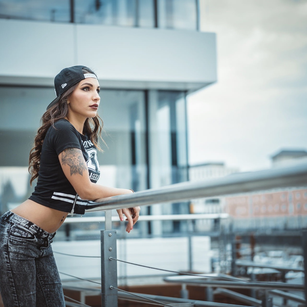 Девушка в кепке с тату смотрит на порт