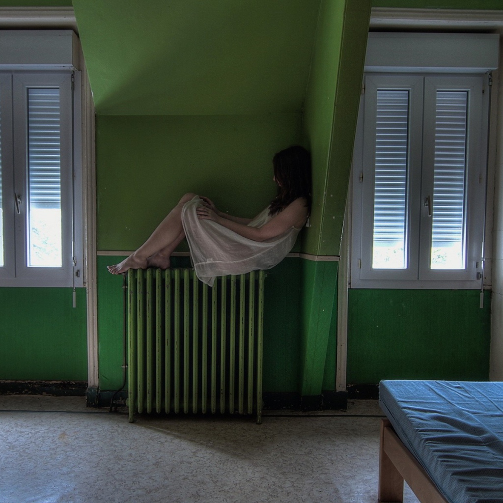 Девушка в ночной рубашке сидит на батарее