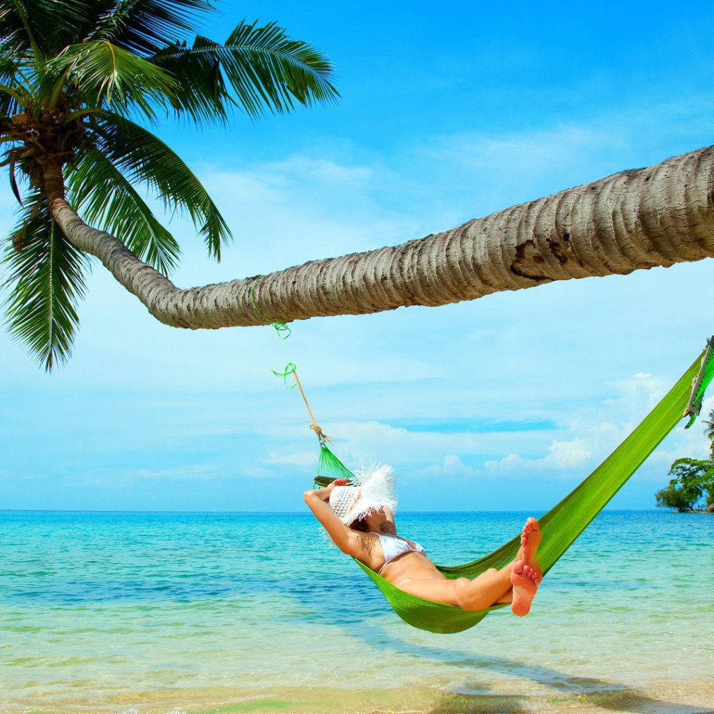 Девушка в зеленом гамаке под пальмой