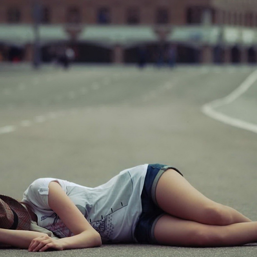 Девушка в шляпе лежит на дороге