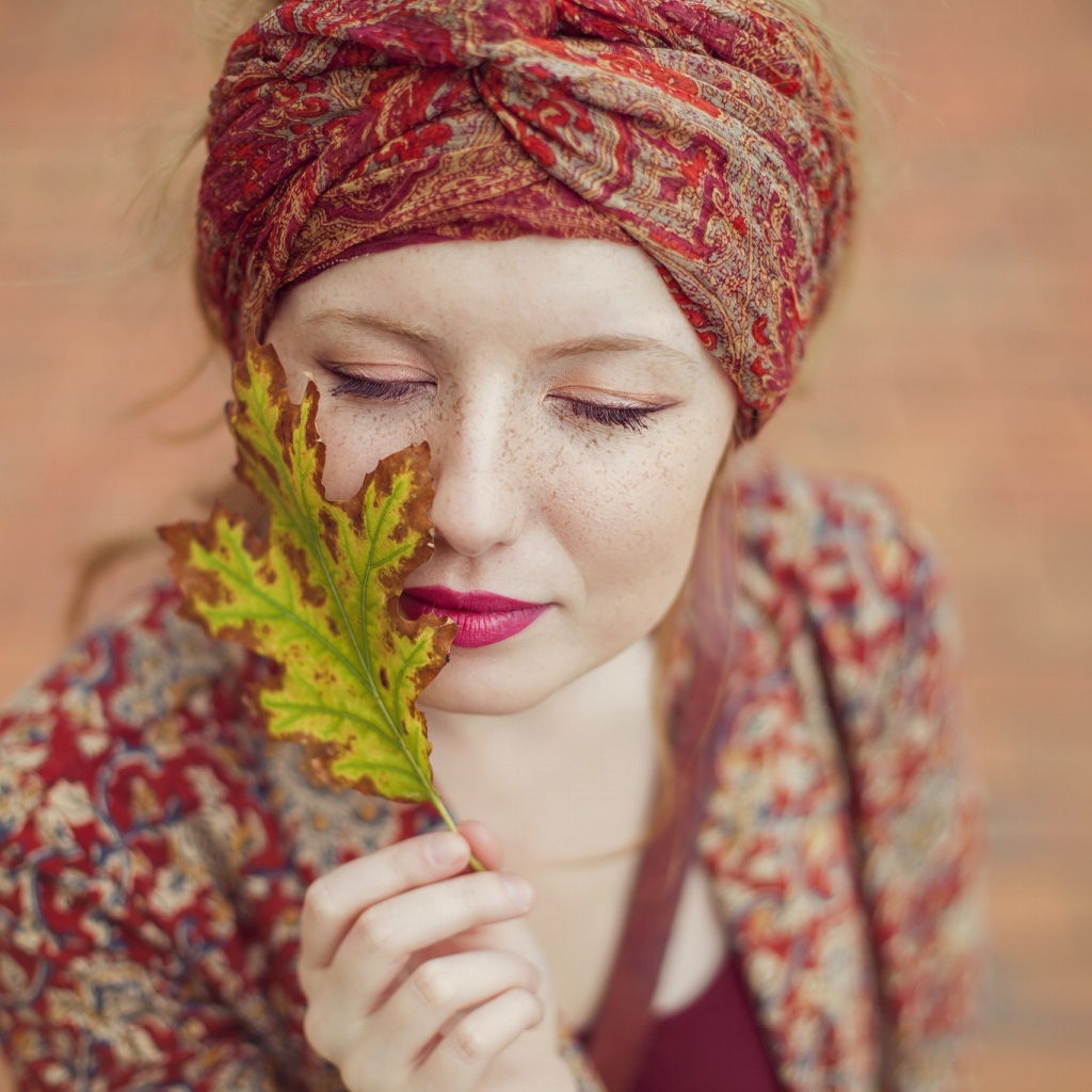 Девушка в традиционном наряде держит в руке лист