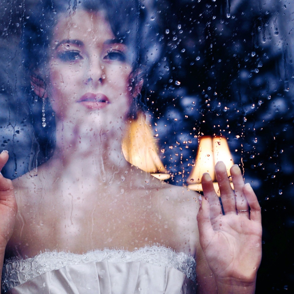 Девушка в белом платье за мокрым стеклом