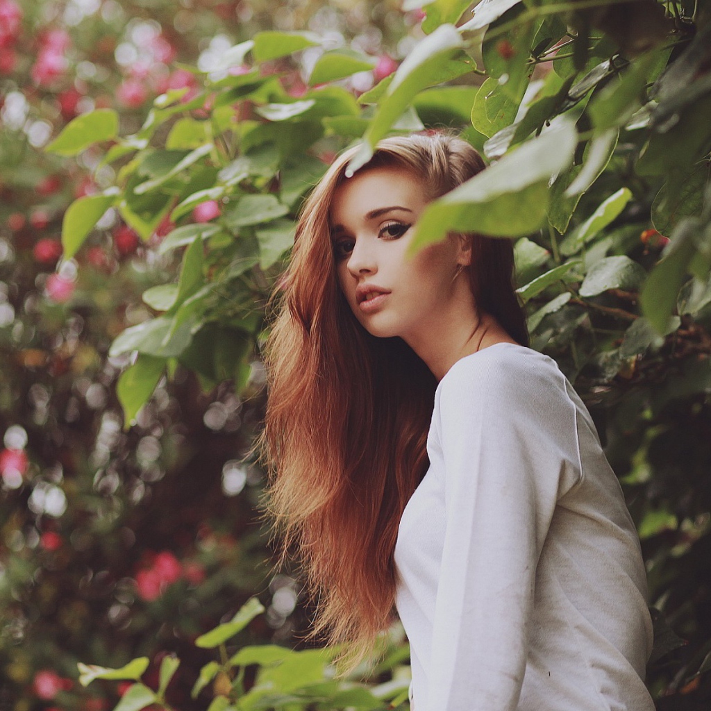 Девушка в белом платье гуляет в саду