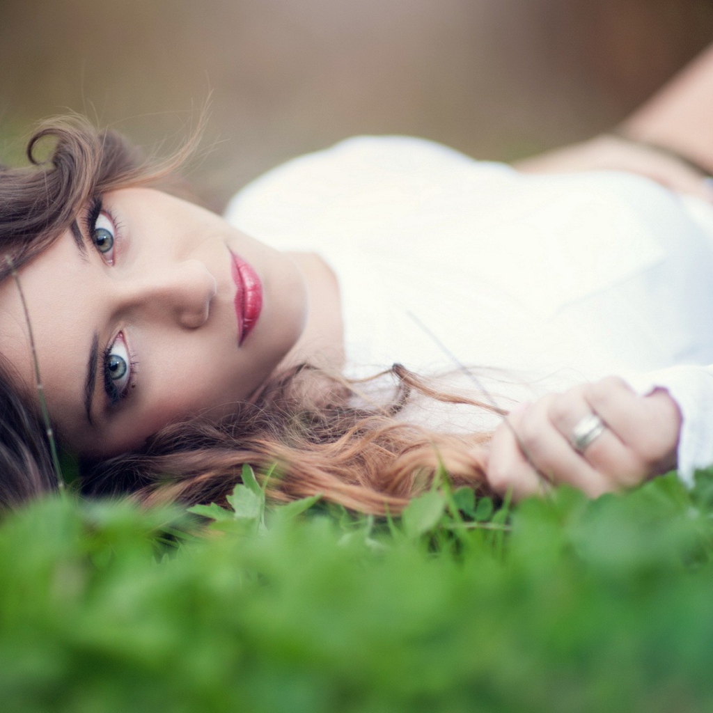 Девушка в белом платье с украшением в волосах лежит на траве