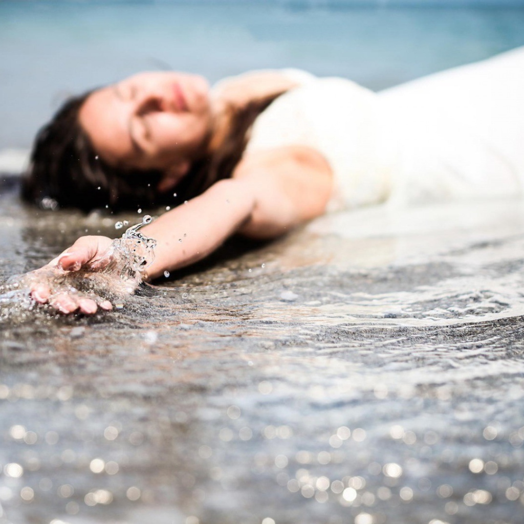 Девушка лежит в волне прибоя