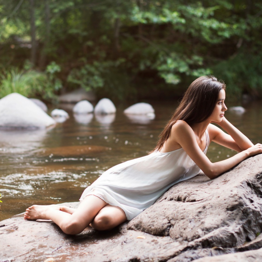 Девушка лежит на камне у реки